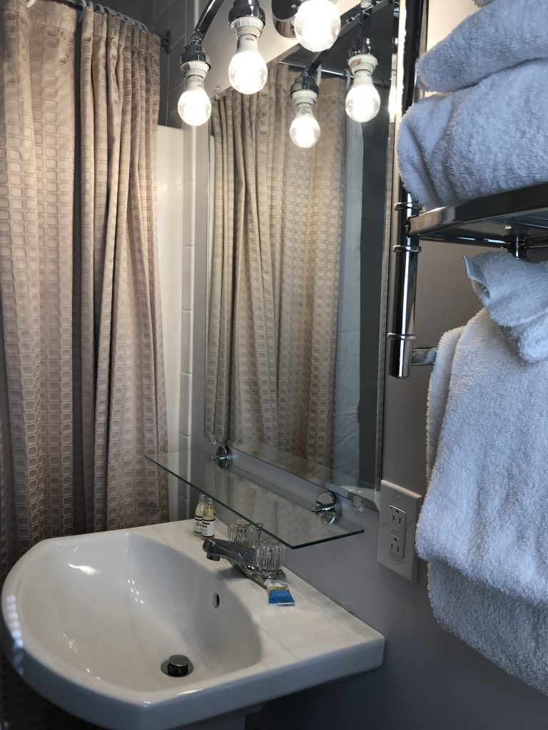 Mirror with glass shelf about pedestal sink