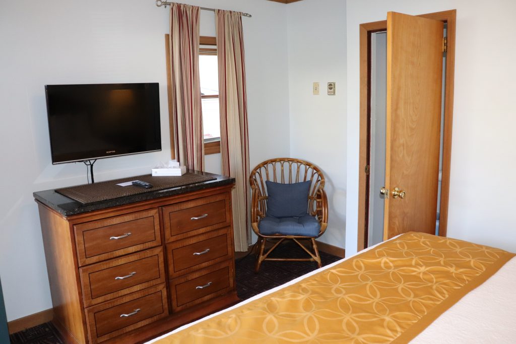 One king bed cottage with dresser and TV and wicker seat
